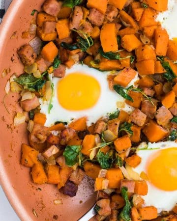 closeup of a skillet with sweet potato hash and fried eggs