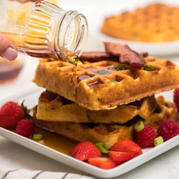 homemade cornmeal waffles on a plate with syrup and bacon