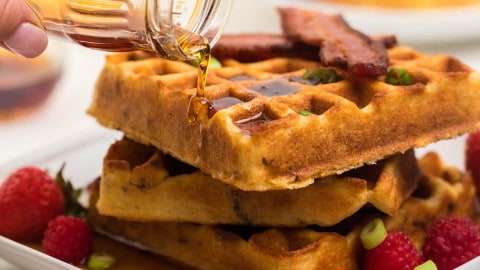 homemade cornmeal waffles on a plate with syrup and bacon