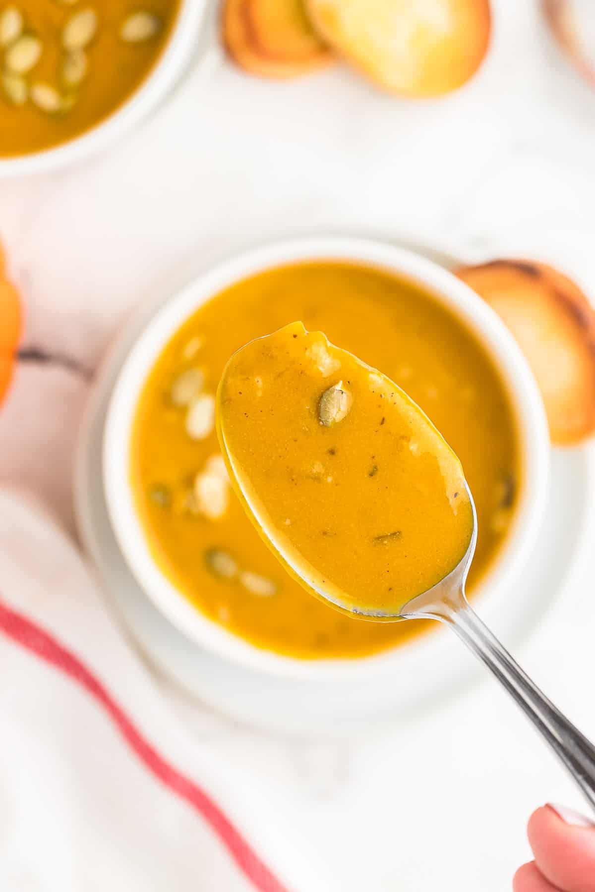 A spoonful of last minute Pumpkin Soup taken from a white bowl.