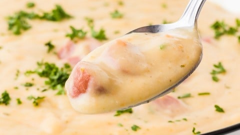A spoonful of creamy German Potato Soup with Wiener sausage served from a white bowl.