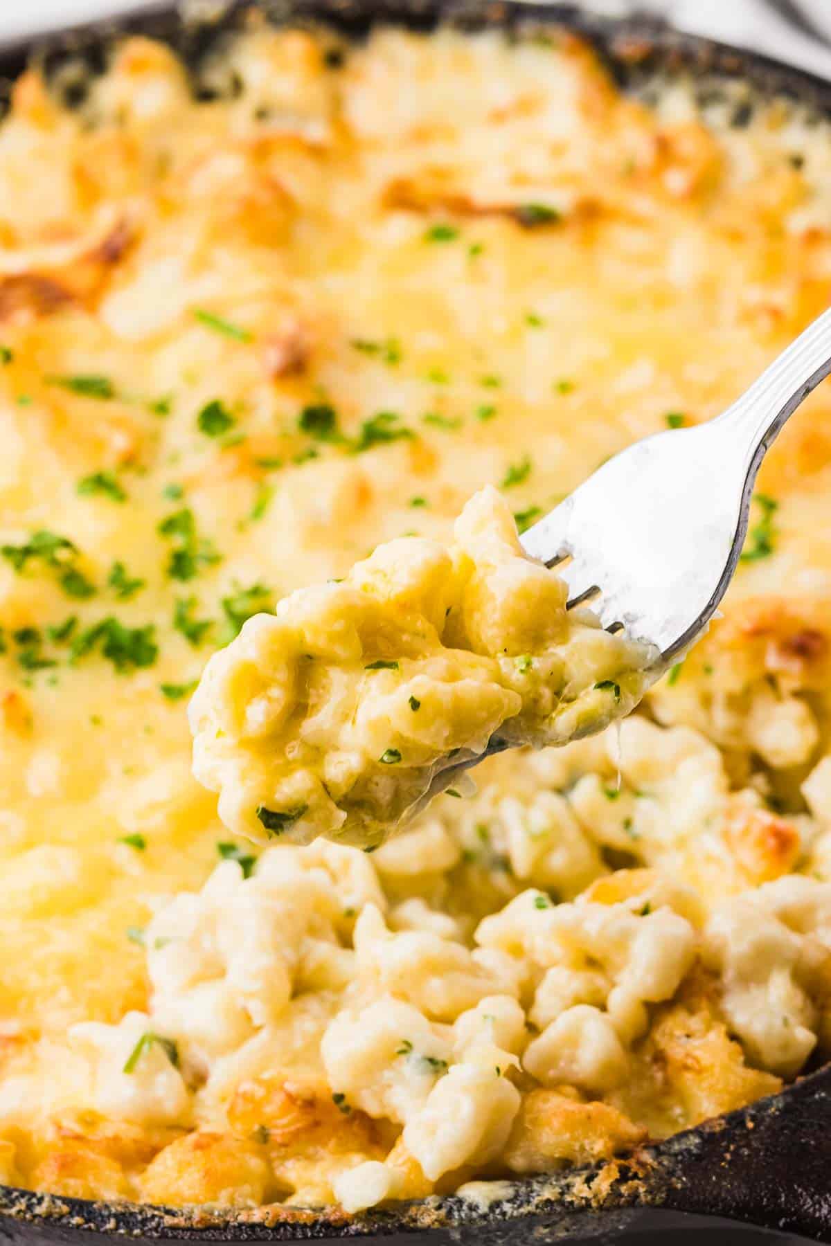 A forkful of Cheese Spaetzle taken from a cast iron skillet. 