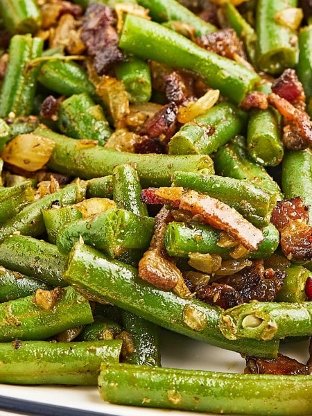 Closeup of Green Beans and Bacon on a white plate.
