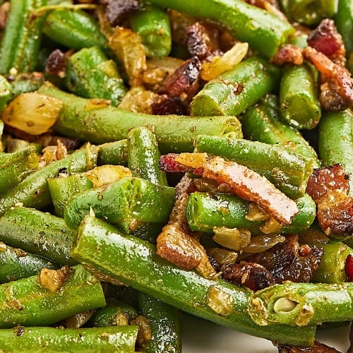 Closeup of Green Beans and Bacon on a white plate.