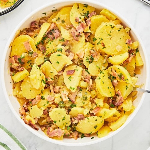 Close-up of Warm German Potato Salad with sliced potatoes in a bacon dressing.