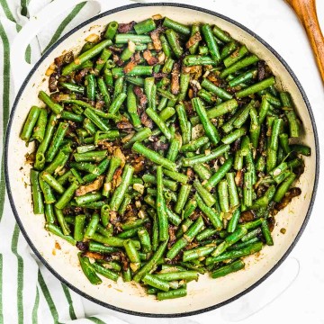 Cooked Green Beans with Bacon and Onions in a white bowl serving dish.