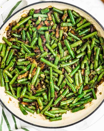 Cooked Green Beans with Bacon and Onions in a white bowl serving dish.