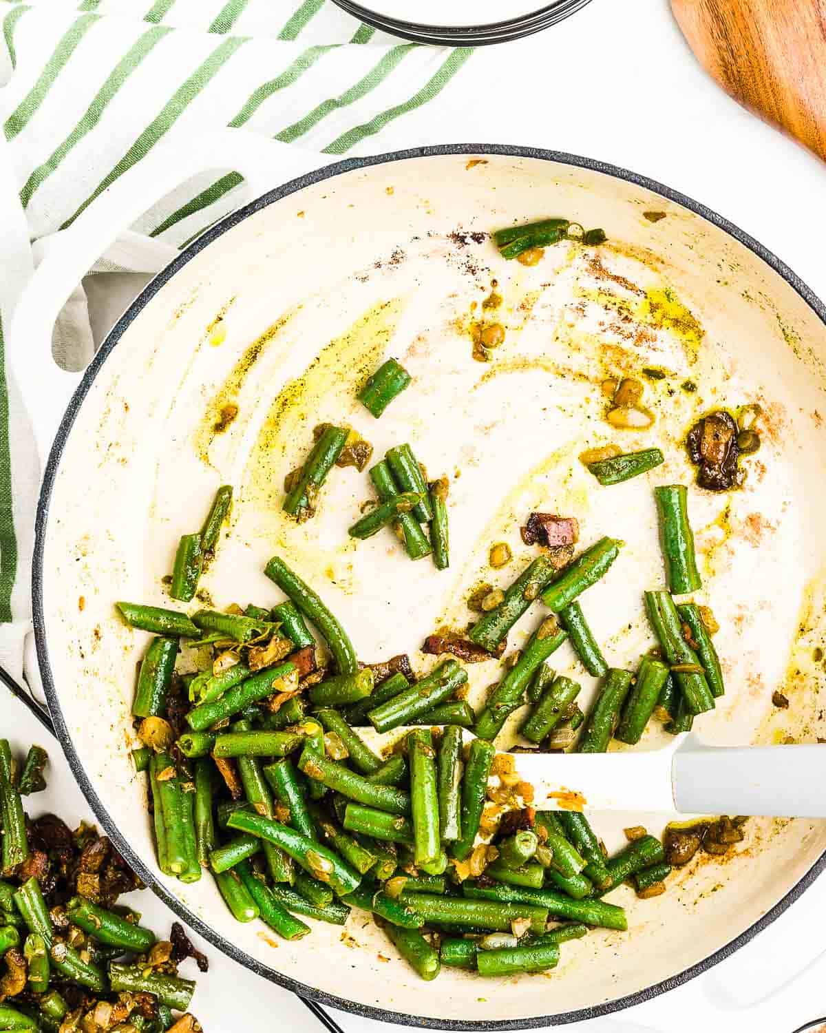 A half-full serving dish of leftover green beans.