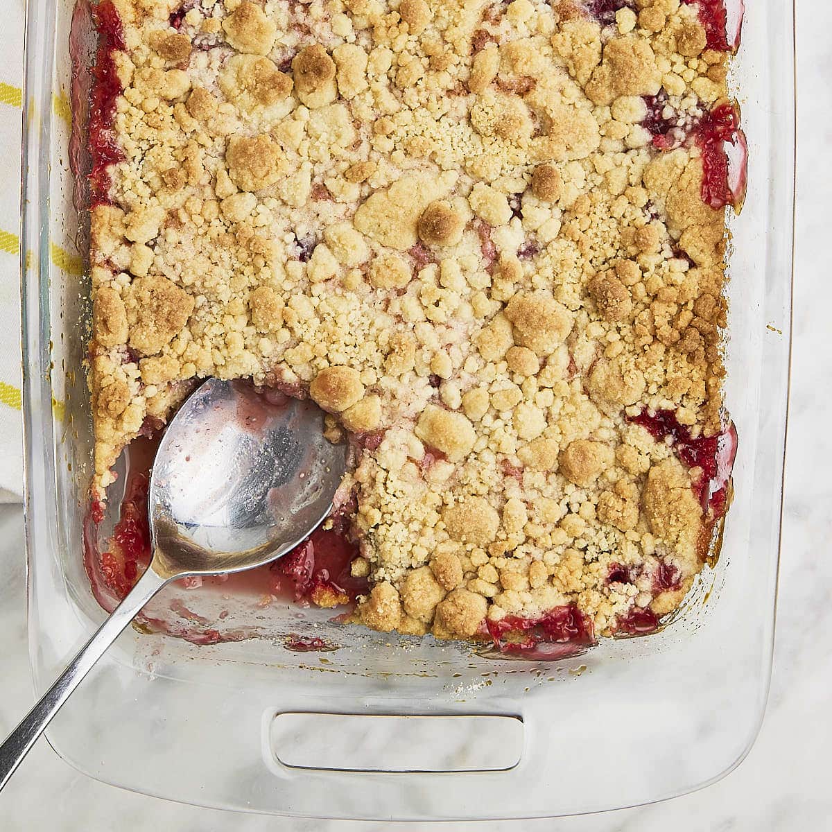 Top down view of a Strawberry Dump Cake in a baking dish with a large serving spoon.