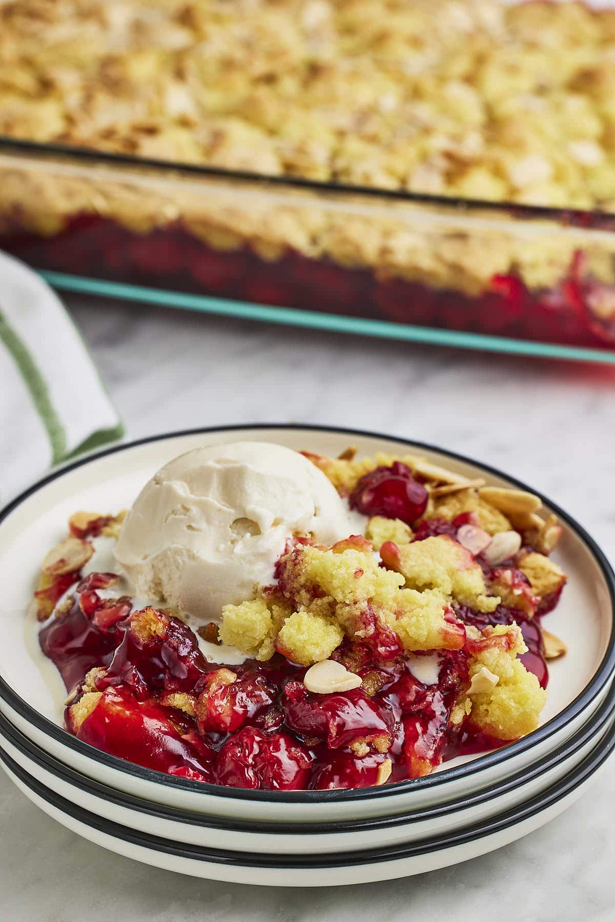 Cherry Dump Cake served on a white plate with vanilla ice cream.