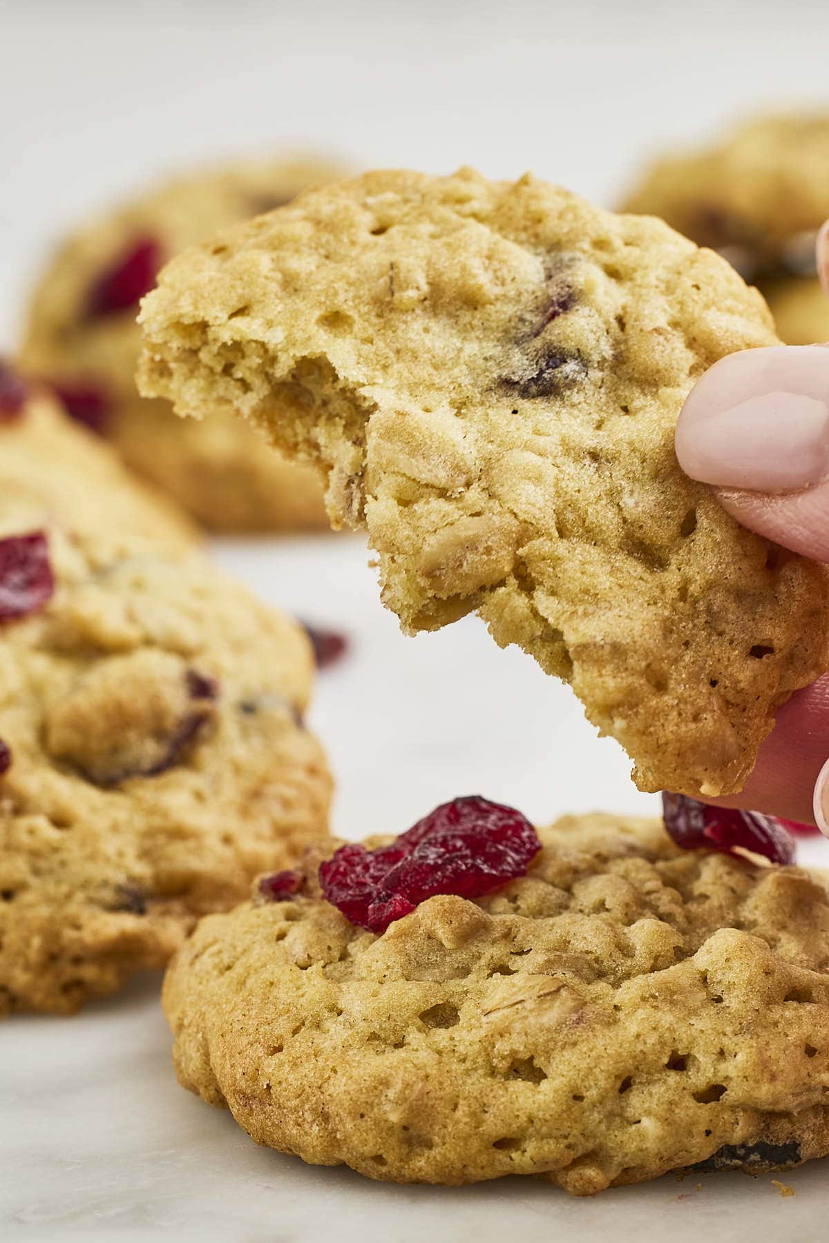 Woman holding a half eaten Cranberry Oatmeal Cookie. 