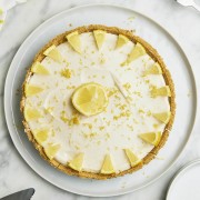 Top down view of a lemon cheesecake served on a white serving platter.