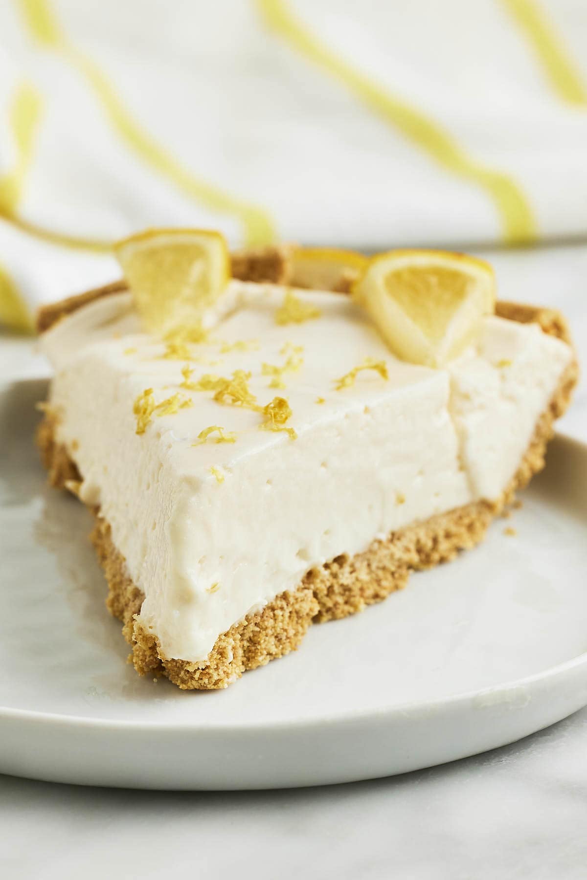 A slice of Lemon Cheesecake on a white plate.