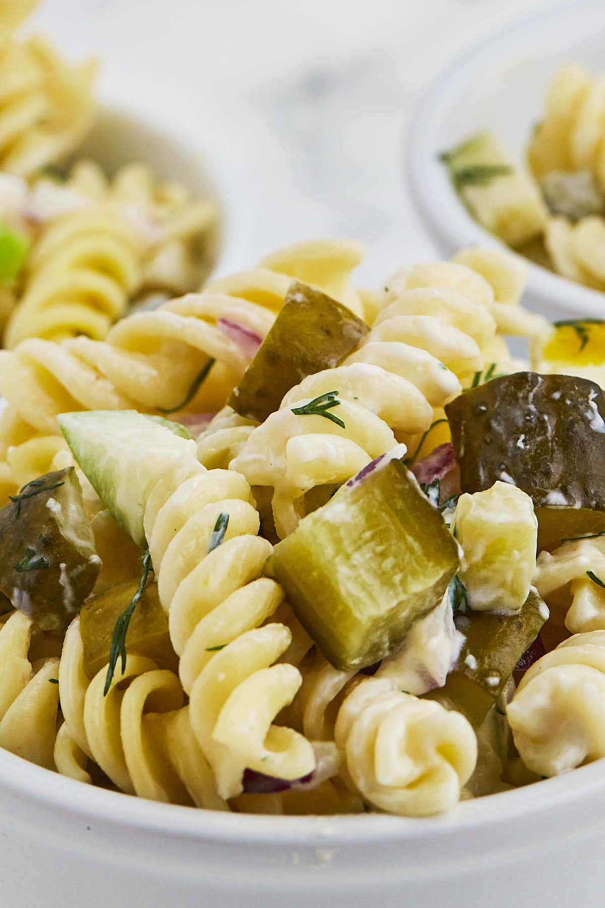 Dill Pickle Pasta Salad in serve in white salad dishes.