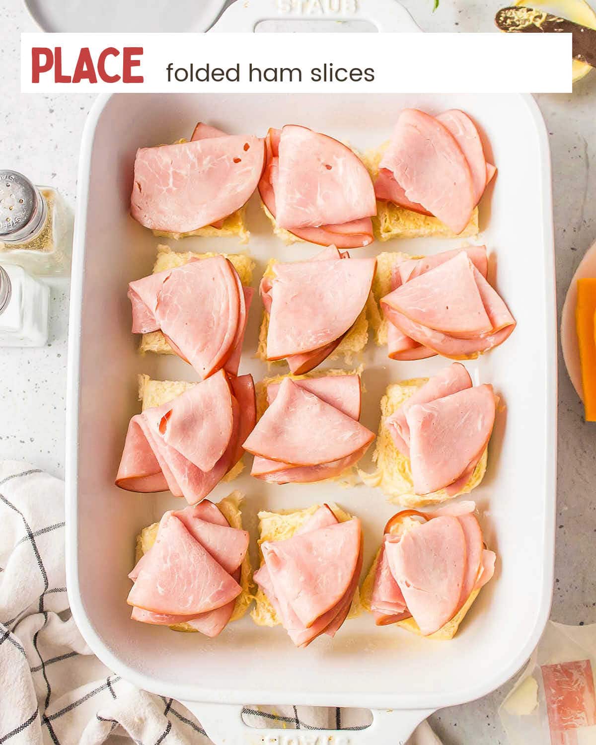 Folded ham slices in a baking dish.