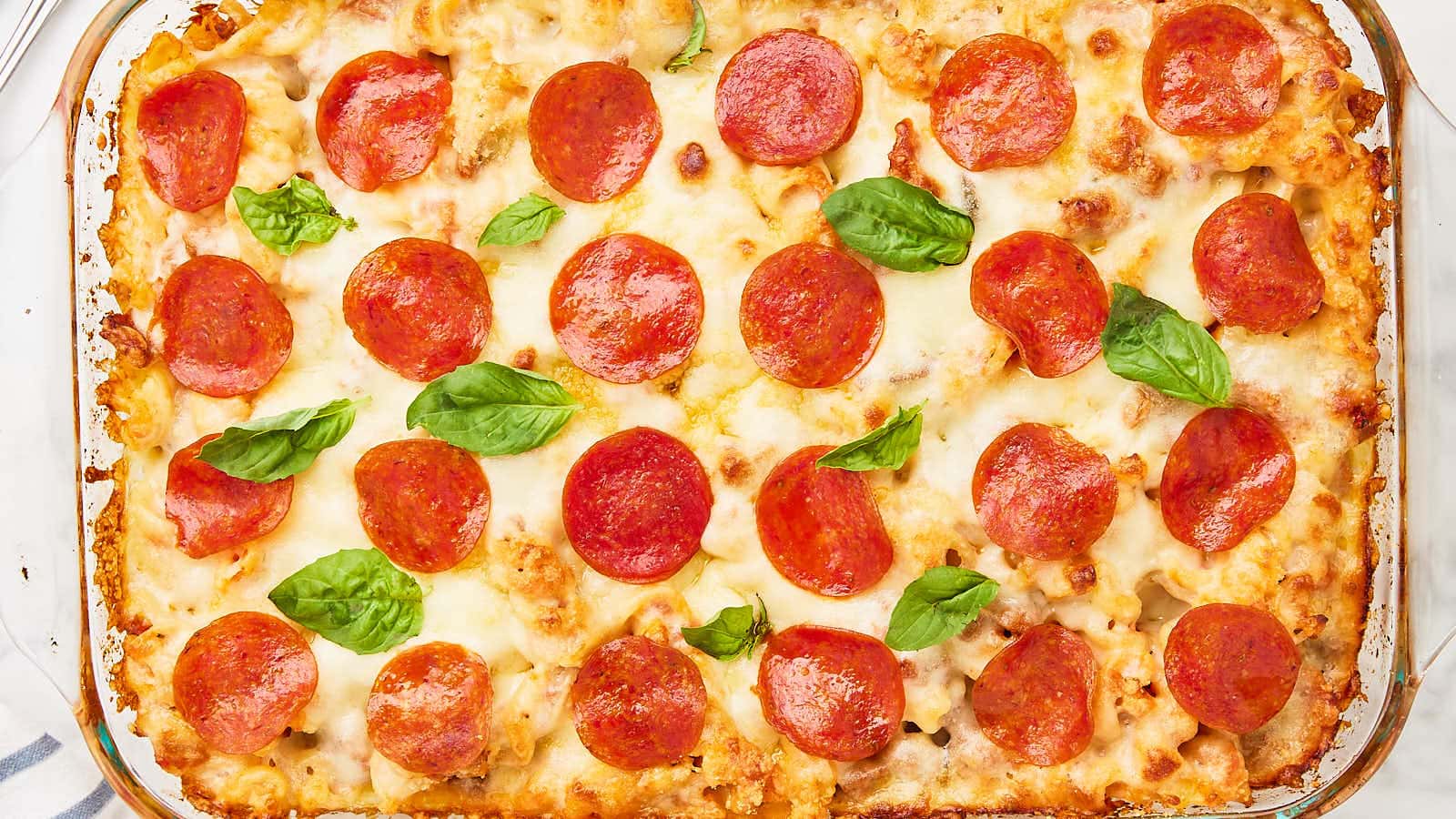 Top down view of a baked Pizza Casserole topped with pepperoni and fresh basil.