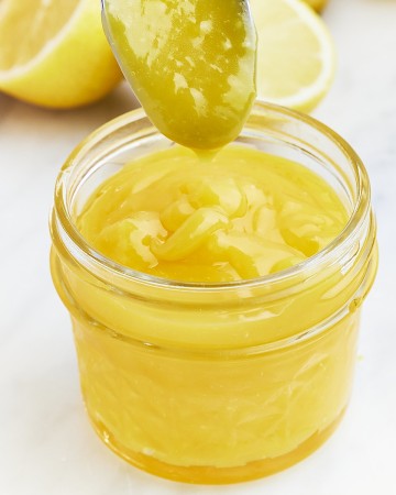 Closeup a bowl of homemade Lemon Curd in a glass jar.