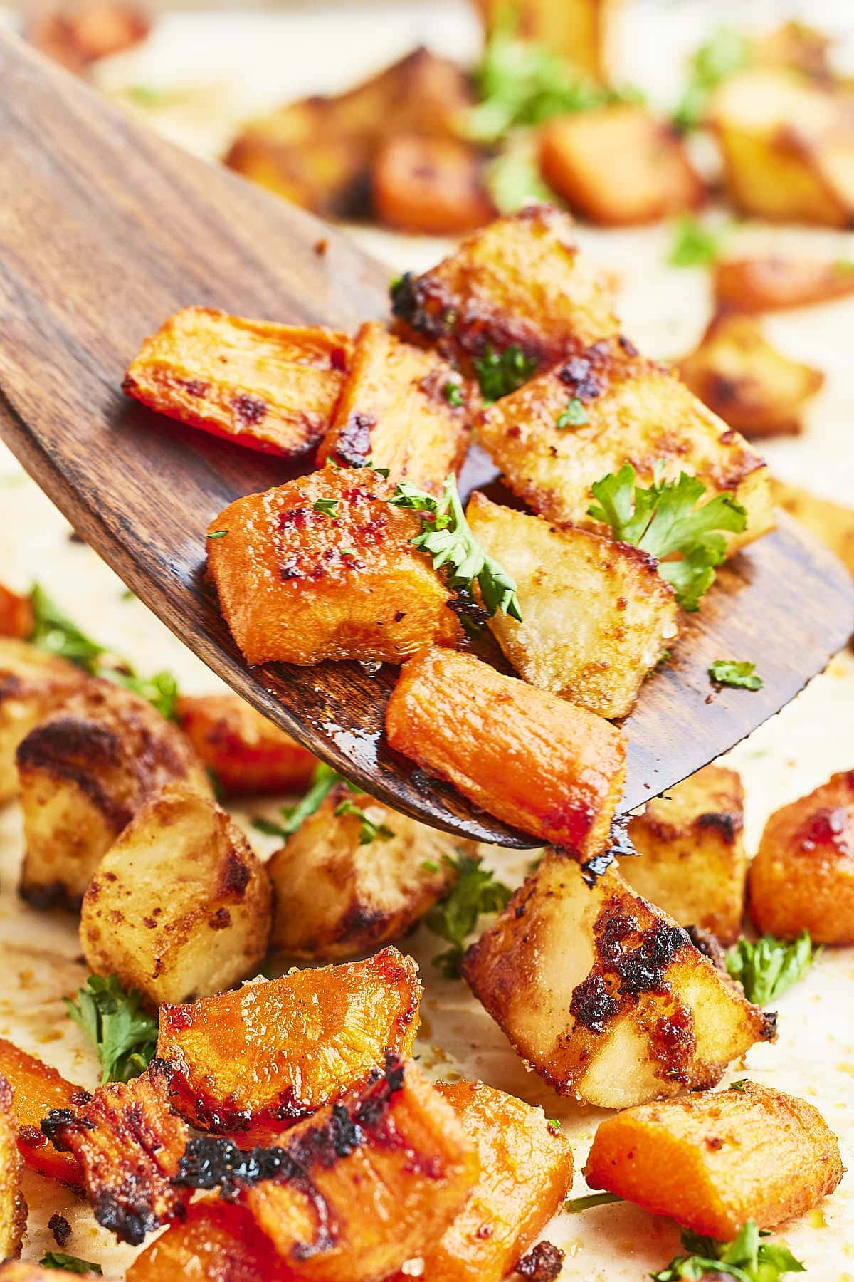 Closeup of Roasted Potatoes and Carrots on a wooden spoon. 