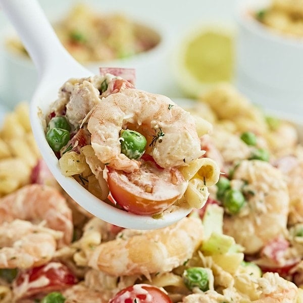 A serving spoon filled with Seafood Pasta Salad.