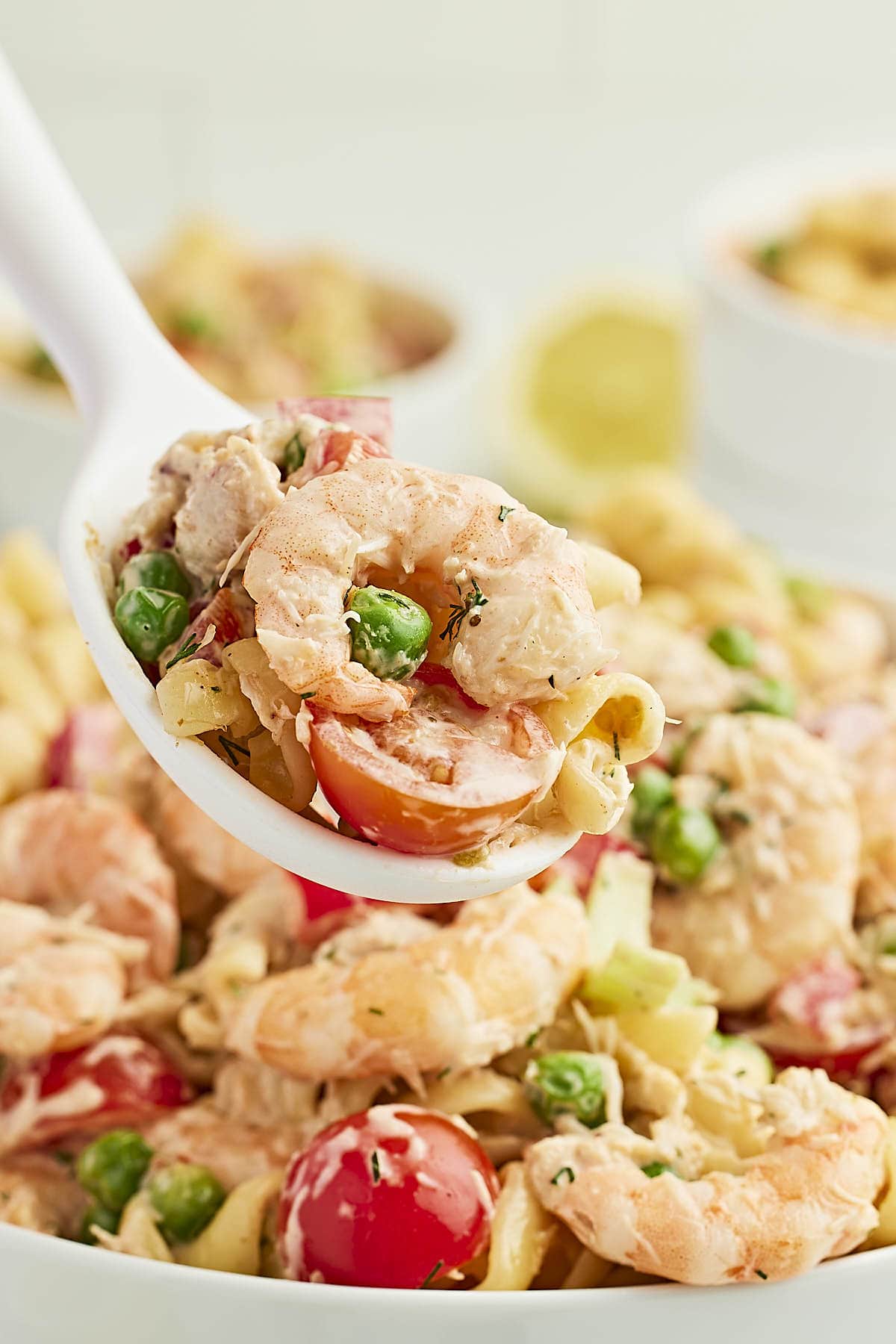 A serving spoon filled with Seafood Pasta Salad.