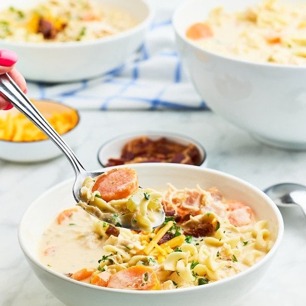 A spoonful of Crack Chicken Noodle Soup served from a white bowl.