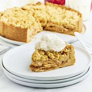 A slice of German Apple Cake topped with whipped cream on a white plate.