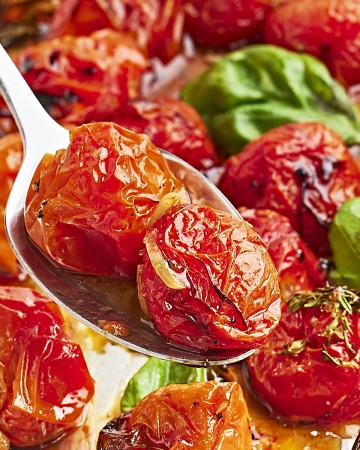 Closeup of a serving spoon loaded with roasted cherry tomatoes.