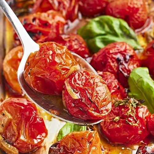 Closeup of a serving spoon loaded with roasted cherry tomatoes.