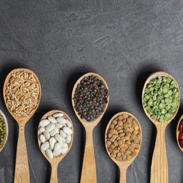 Different types of beans on wooden spoons.