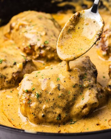 Closeup of creamy chicken served in a cast iron skillet.