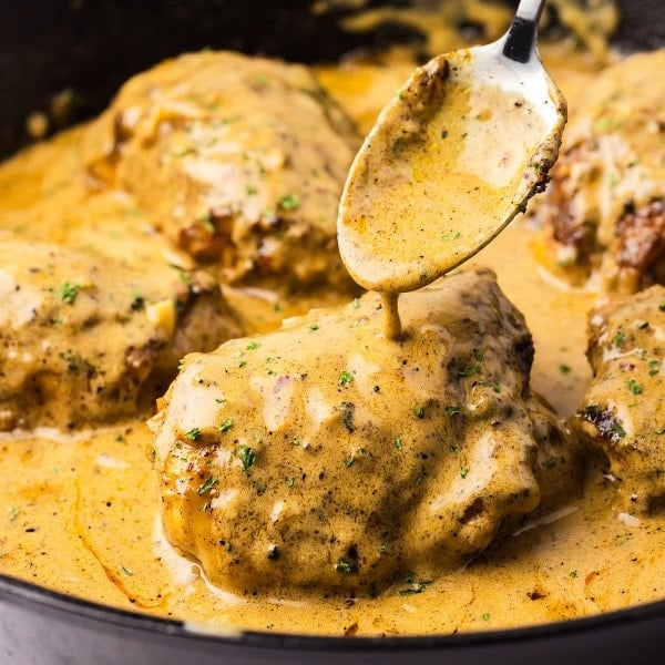 Closeup of creamy chicken served in a cast iron skillet.