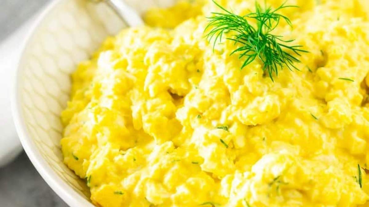 A bowl of scrambled eggs with dill.