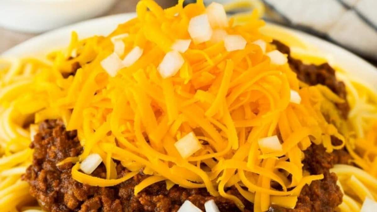 A plate of spaghetti with chili and cheese on top.