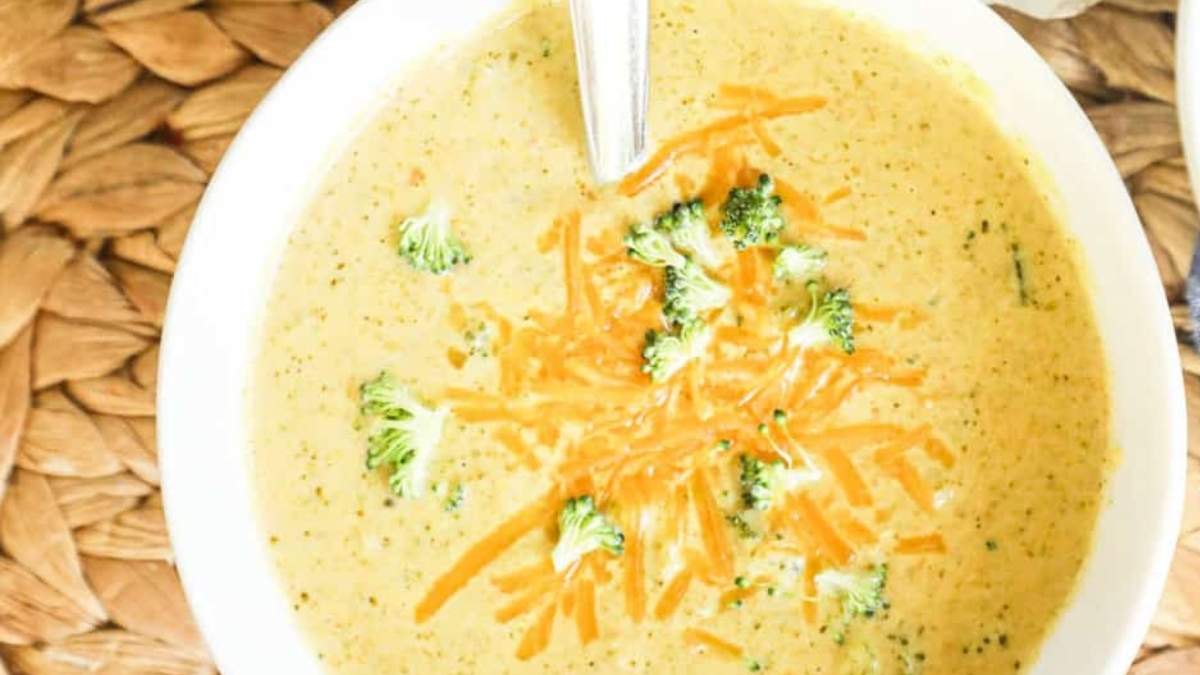 A bowl of broccoli cheese soup with a spoon.