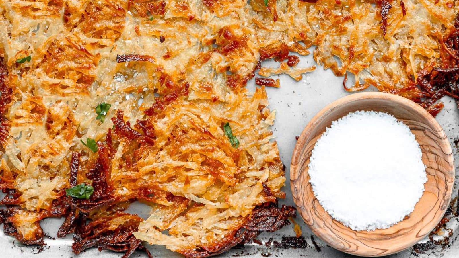 Crispy hash browns with a bowl of salt nearby.