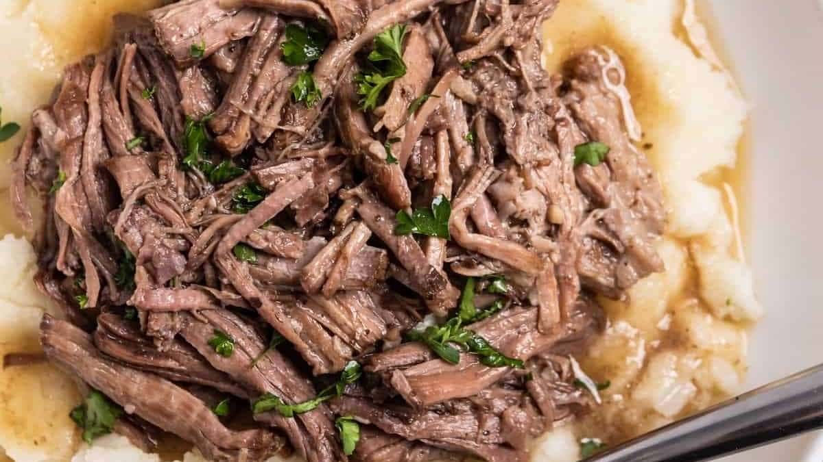 A bowl of beef and mashed potatoes with gravy.