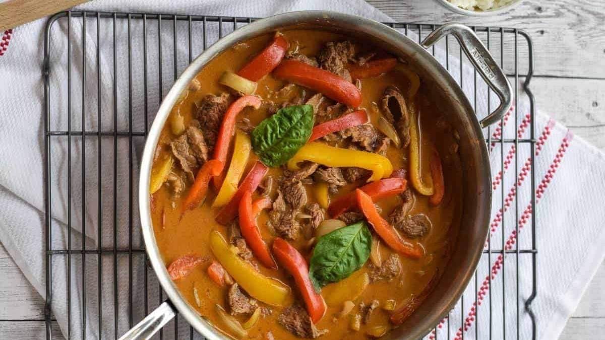 Thai beef curry in a pan with peppers and basil.