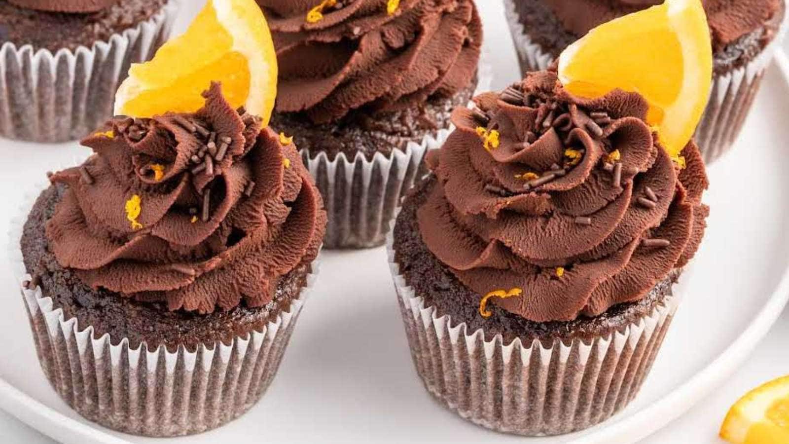 A plate of chocolate cupcakes adorned with fresh orange slices.