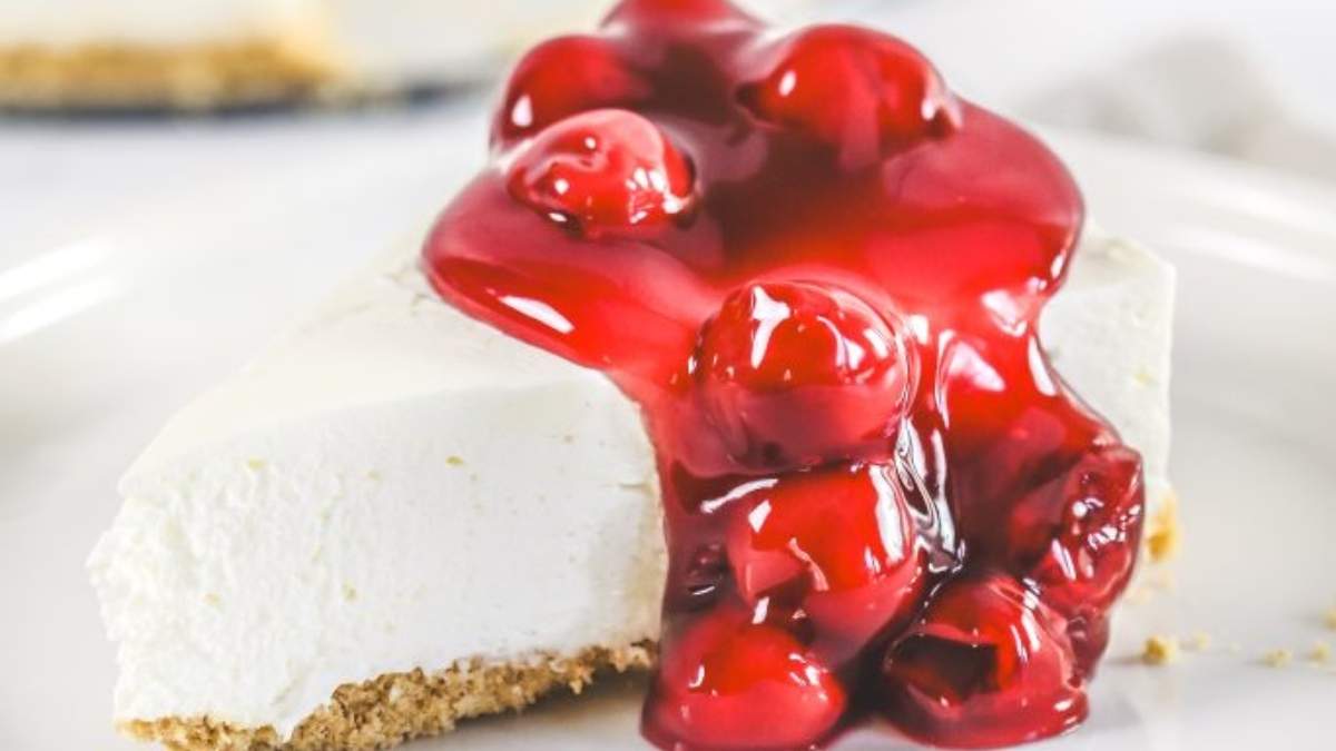 A slice of cherry cheesecake, one of the most delicious no-bake desserts, presented on a simple white plate.