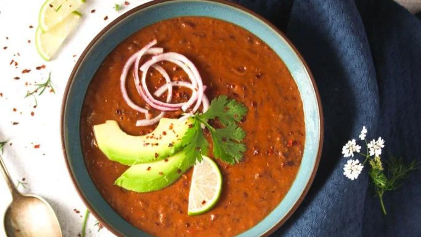  A bowl of black bean soup with onion slices.