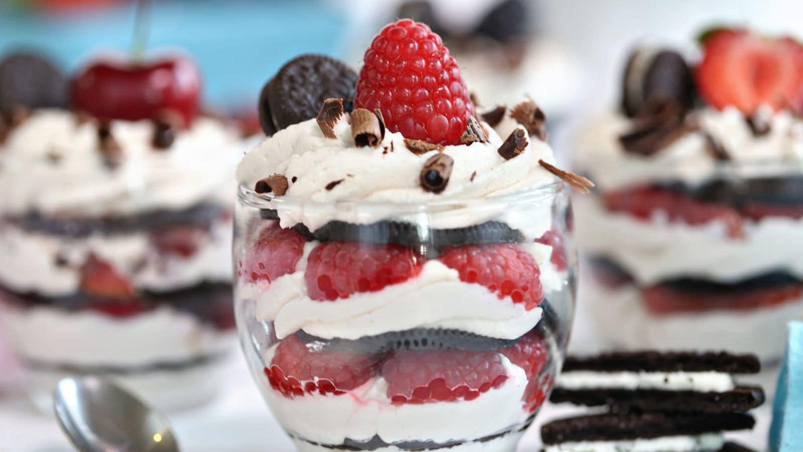Parfait cups with Oreo cookies, whipped cream, and berries.