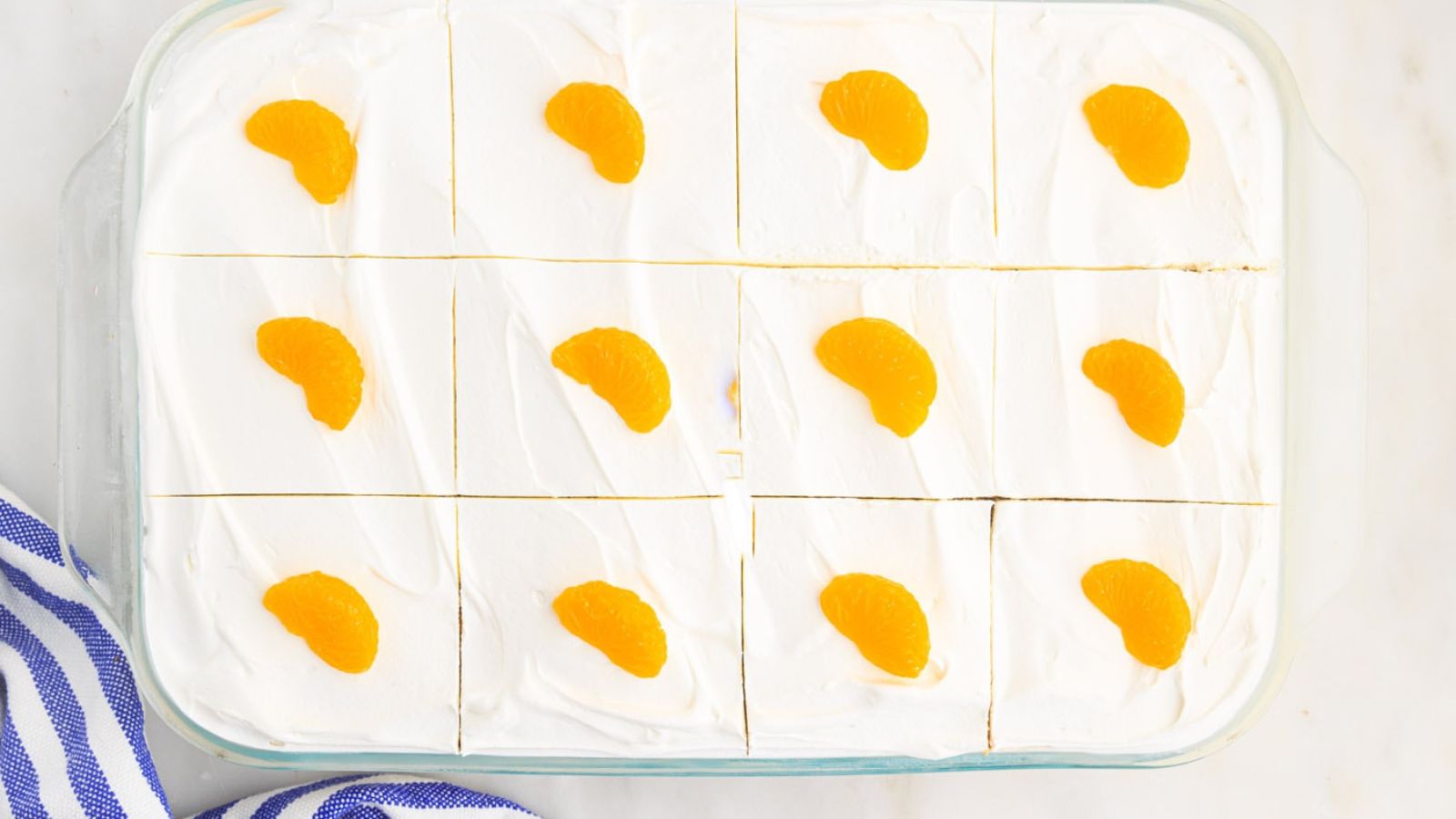 A cake sliced into squares with orange segments on top.
