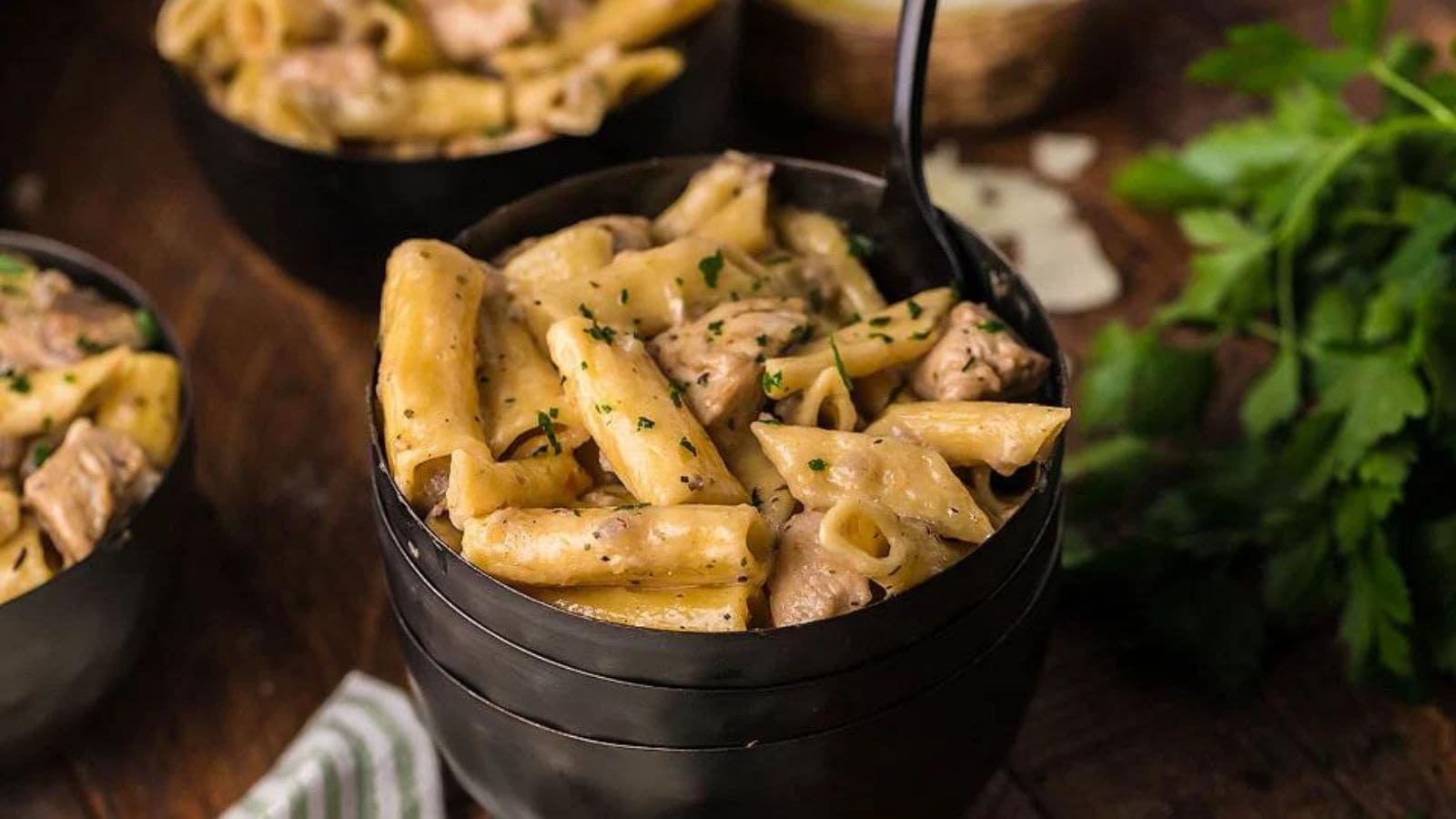 A bowl of pasta with garlic sauce and chicken chunks.