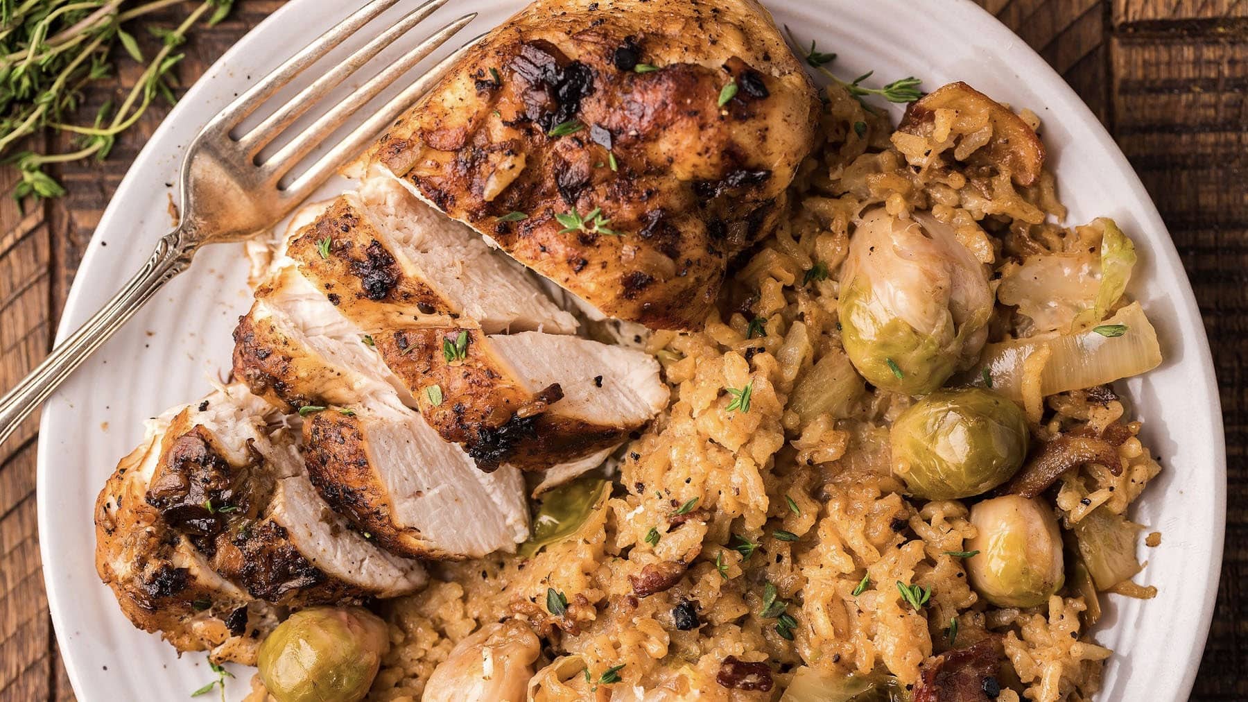 Roasted chicken with brussels sprouts and rice on a plate.