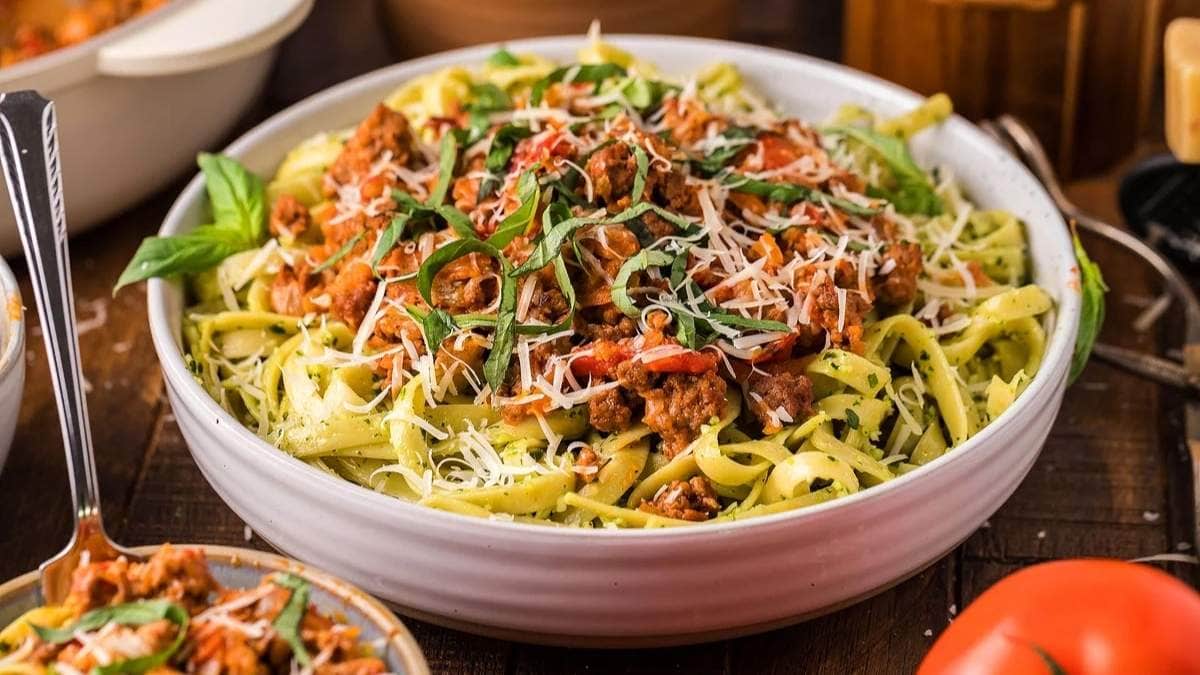 A bowl of pasta with meat, tomatoes and basil.