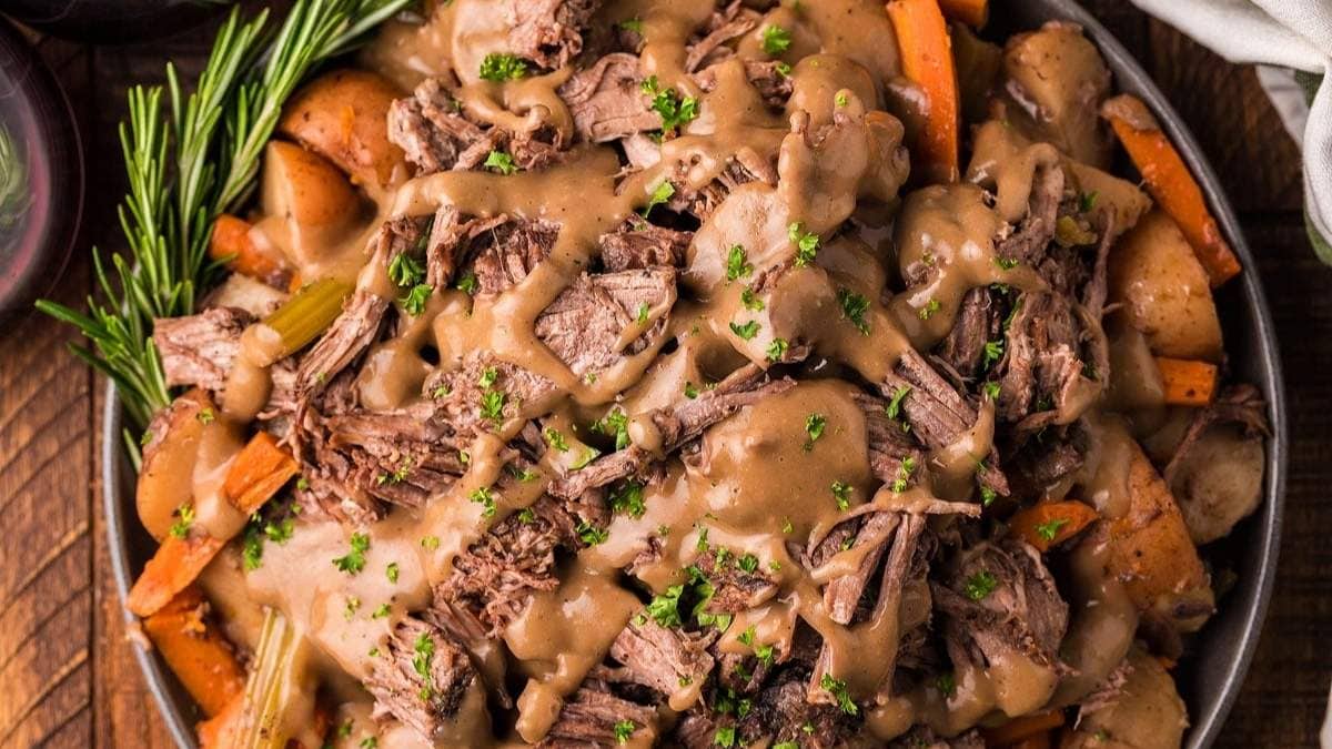 Roasted beef with gravy and carrots on a plate.
