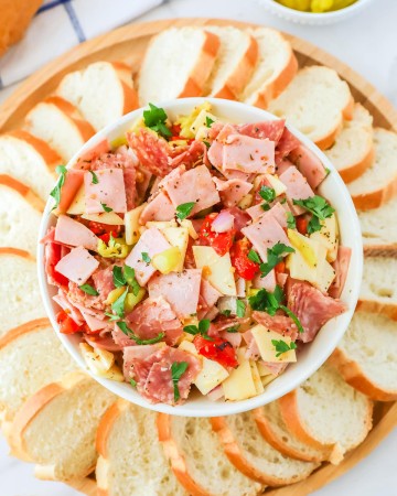 An Italian Hoagie Dip with bread and pickles.