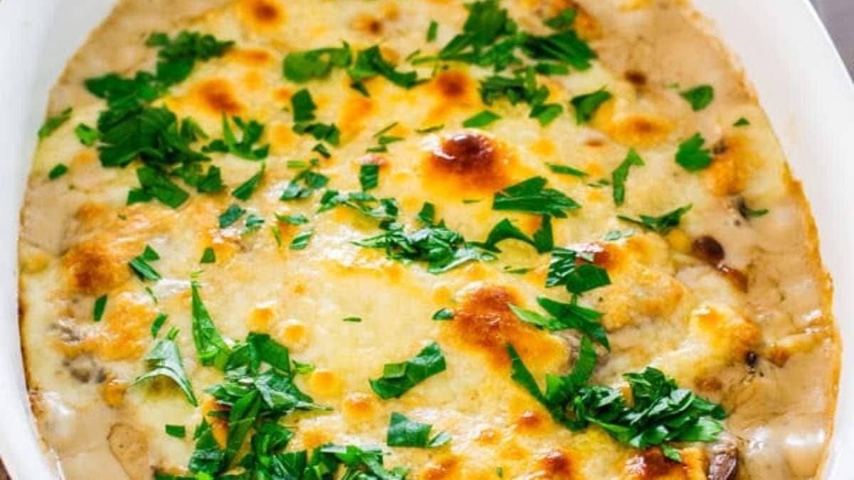 Cheesy mushroom casserole in a white dish with parsley.