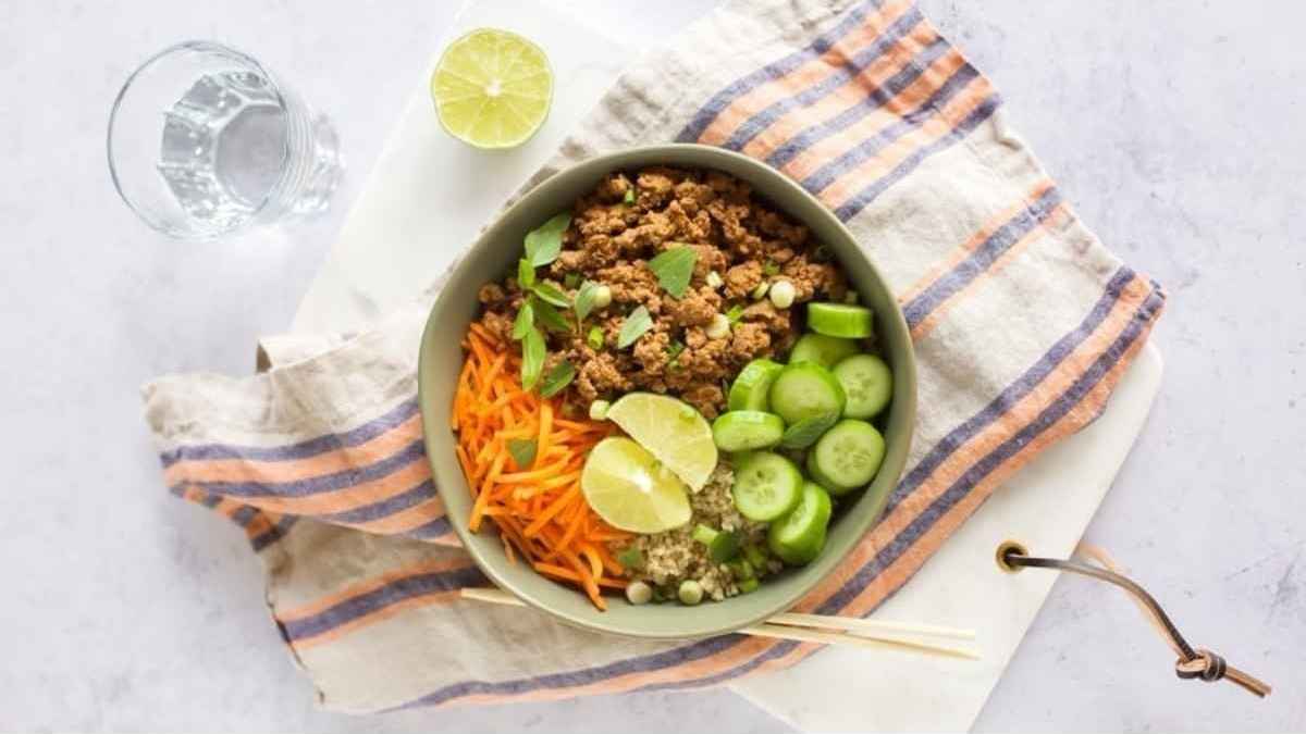 A bowl of meat and vegetables with a spoon and chopsticks.