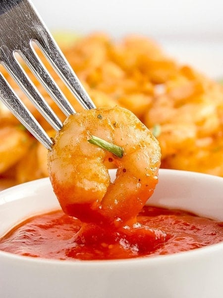 A fork is dipping Thai Red Curry Chicken into a bowl of sauce.